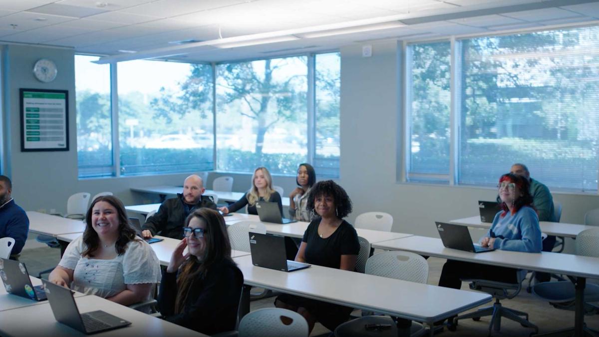 a group of people sitting at tables with laptops