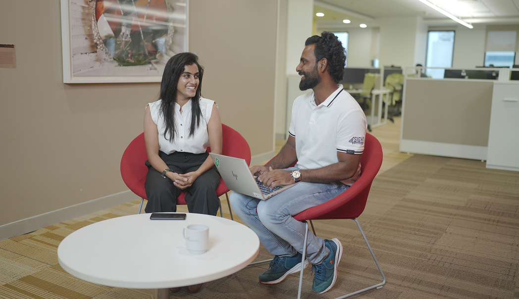 a person and person sitting in chairs with a laptop