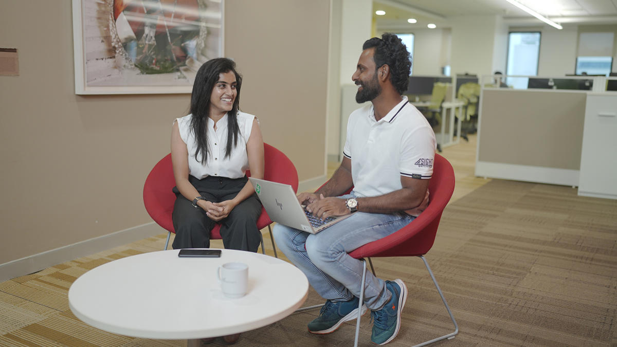 a person and person sitting in chairs with a laptop