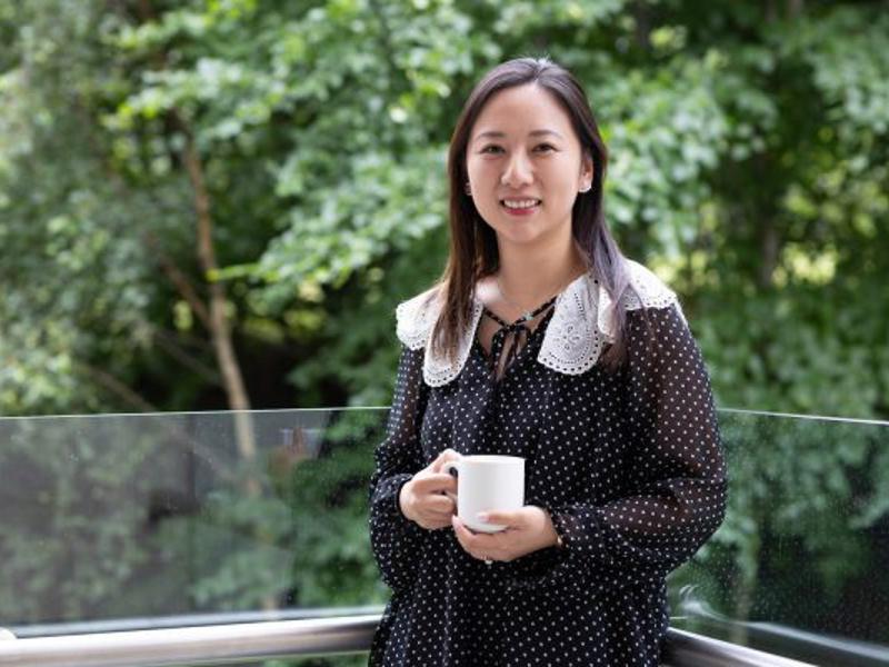 Woman Smiling Outside Coffee Green Trees 600X400