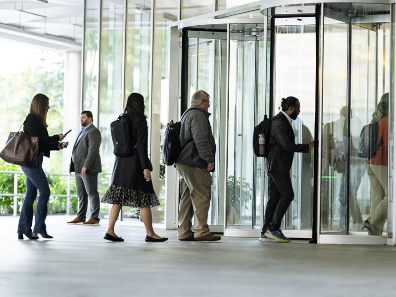 a group of people walking through a glass building
