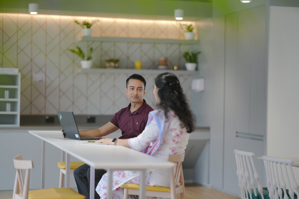 Two people sitting together at a table in an office cafeteria