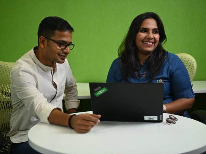 a person and person sitting at a table looking at a laptop