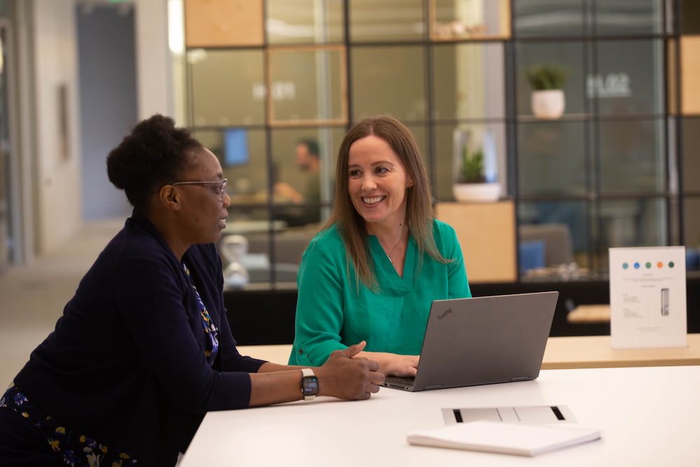 Two women talking to one another in front of a laptop