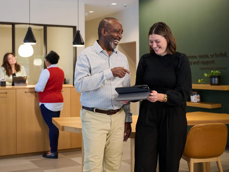 a person and person standing in a room with a laptop