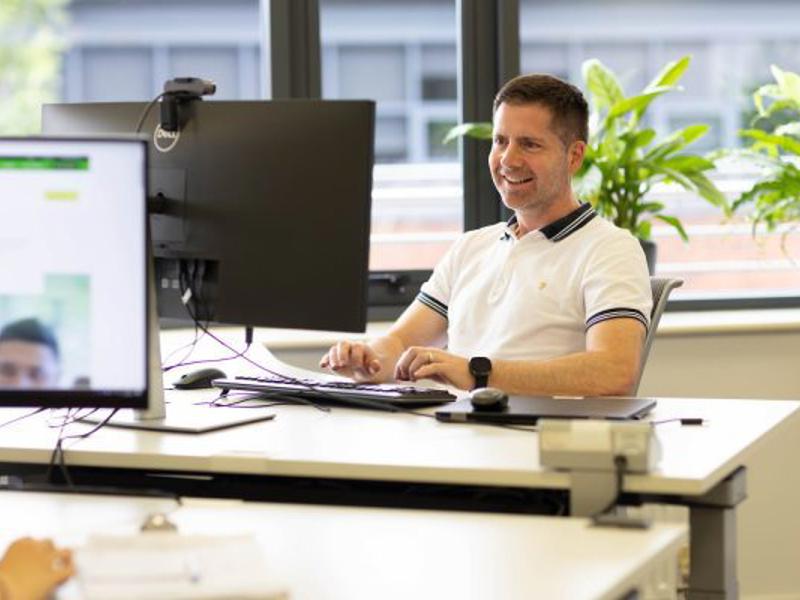 Person Smiling Computer Desk Sunny Office 600X400