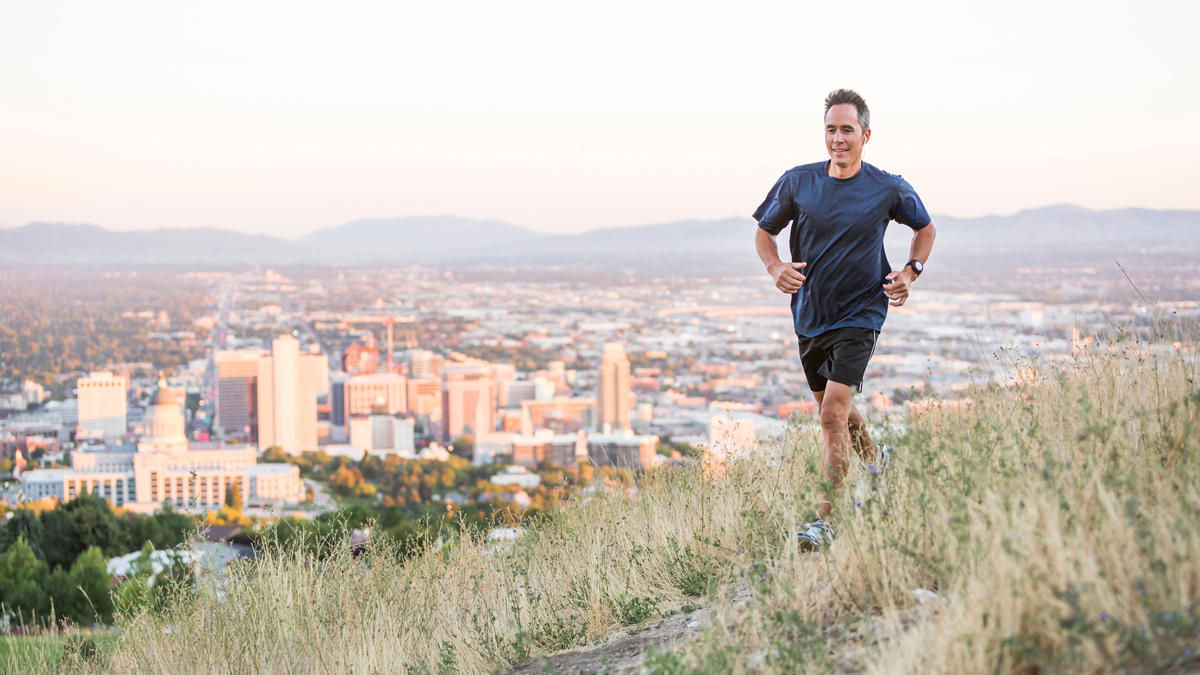 a person running on a hill with a city in the background