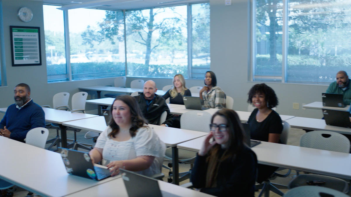 a group of people sitting at desks with laptops