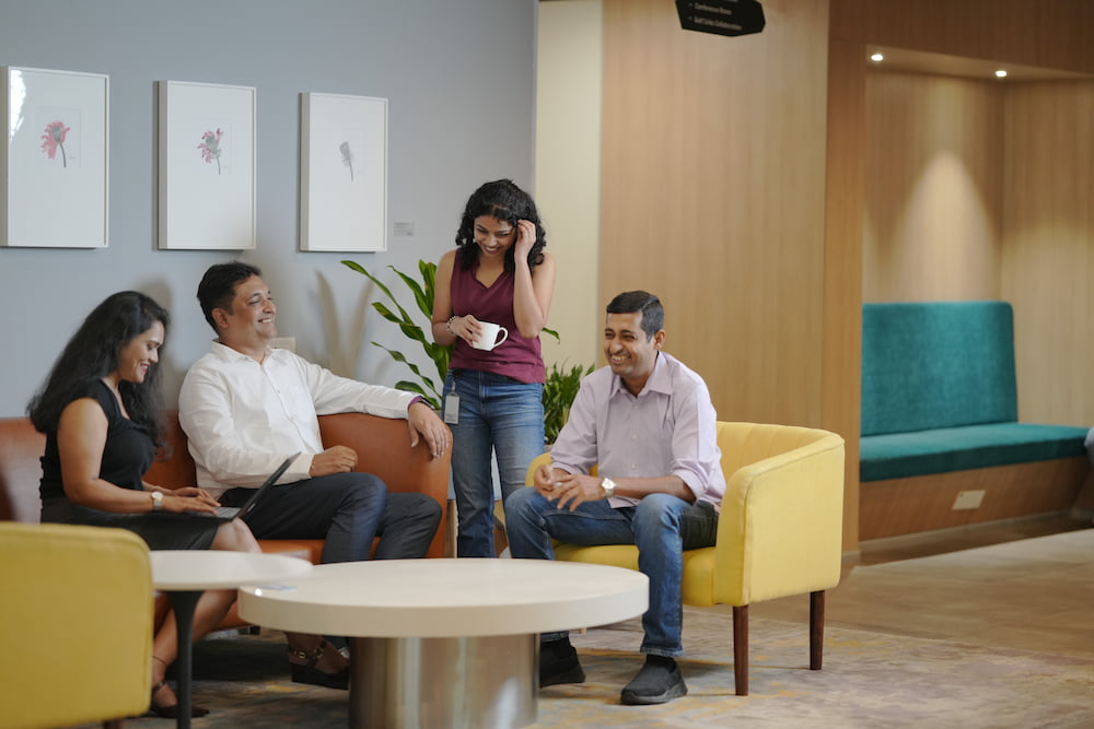 A group of people casually chatting around a coffee table in an office
