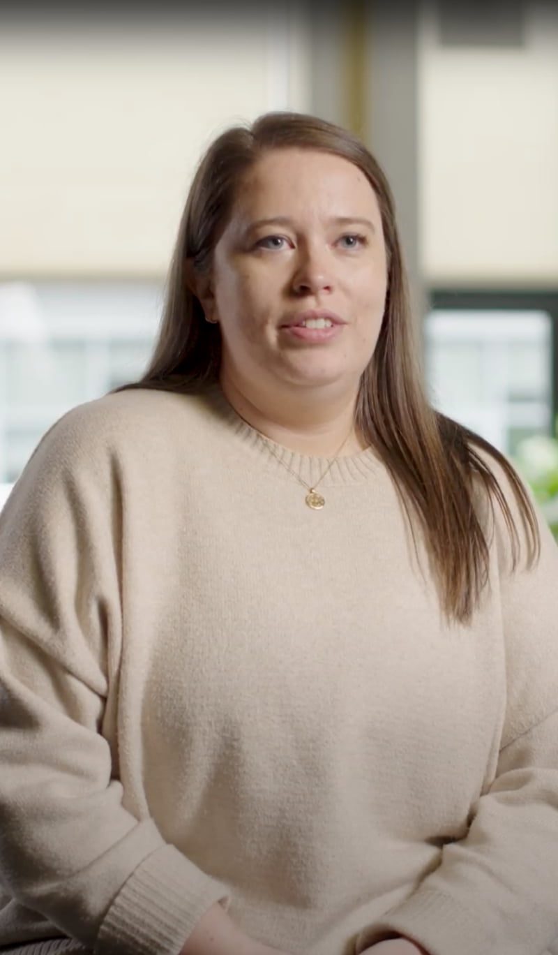 a person with long hair wearing a beige sweater