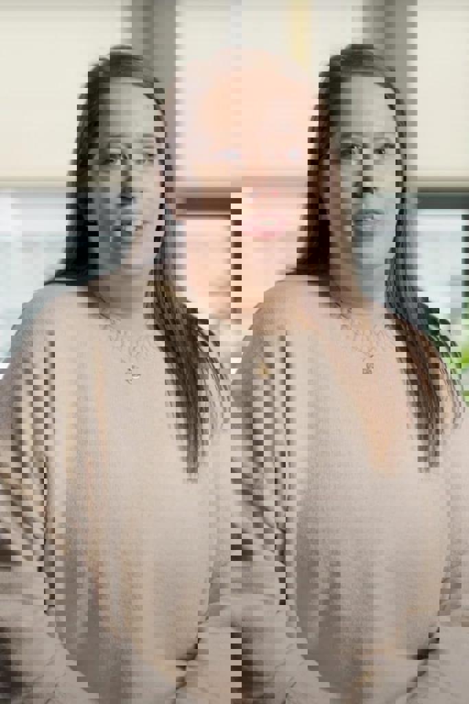 a person with long hair wearing a beige sweater