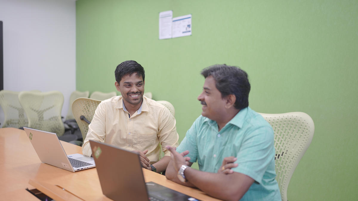 a group of men sitting at a table with a laptop