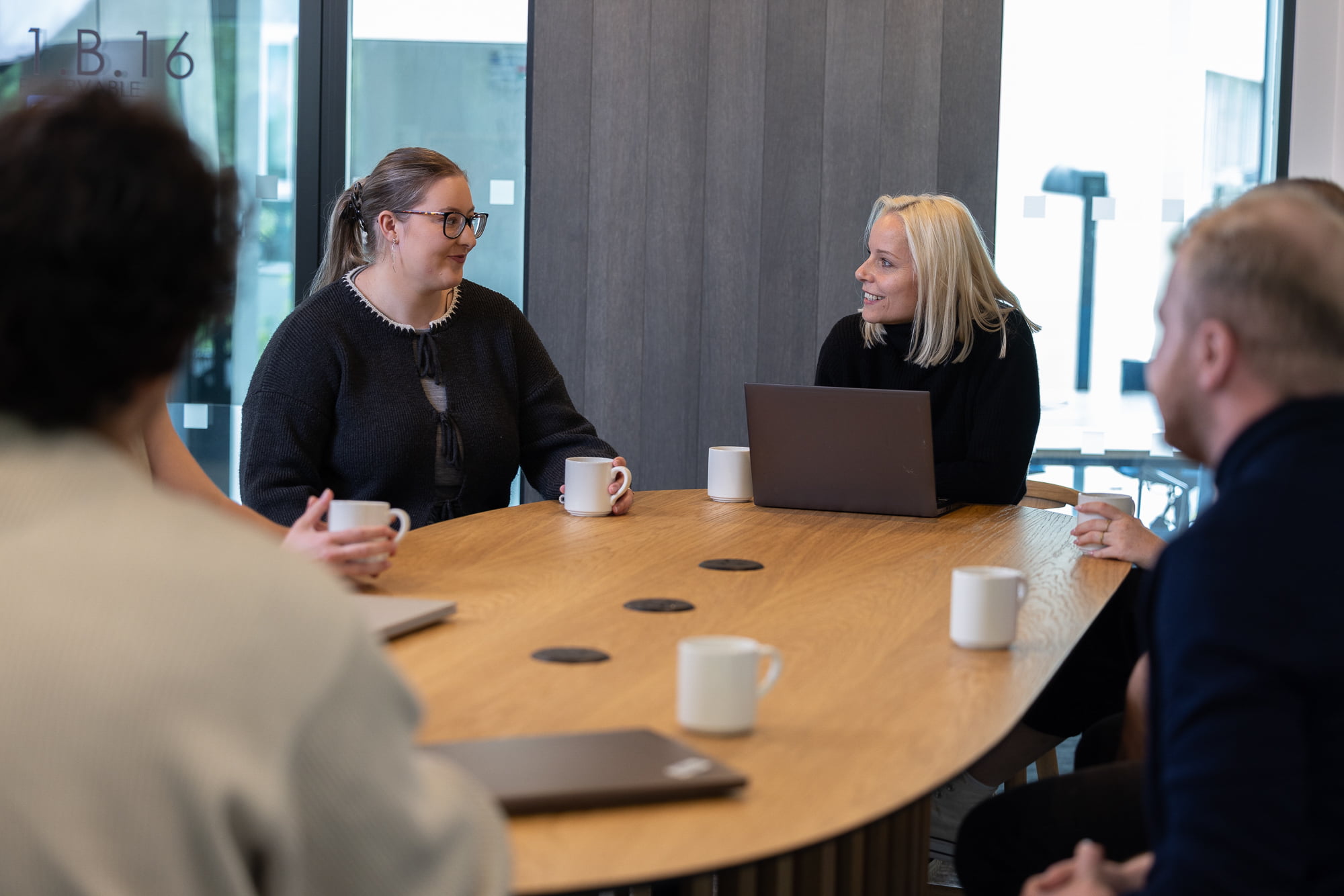 A group of Fidelity associates sitting around a table with coffee mugs and laptops on it