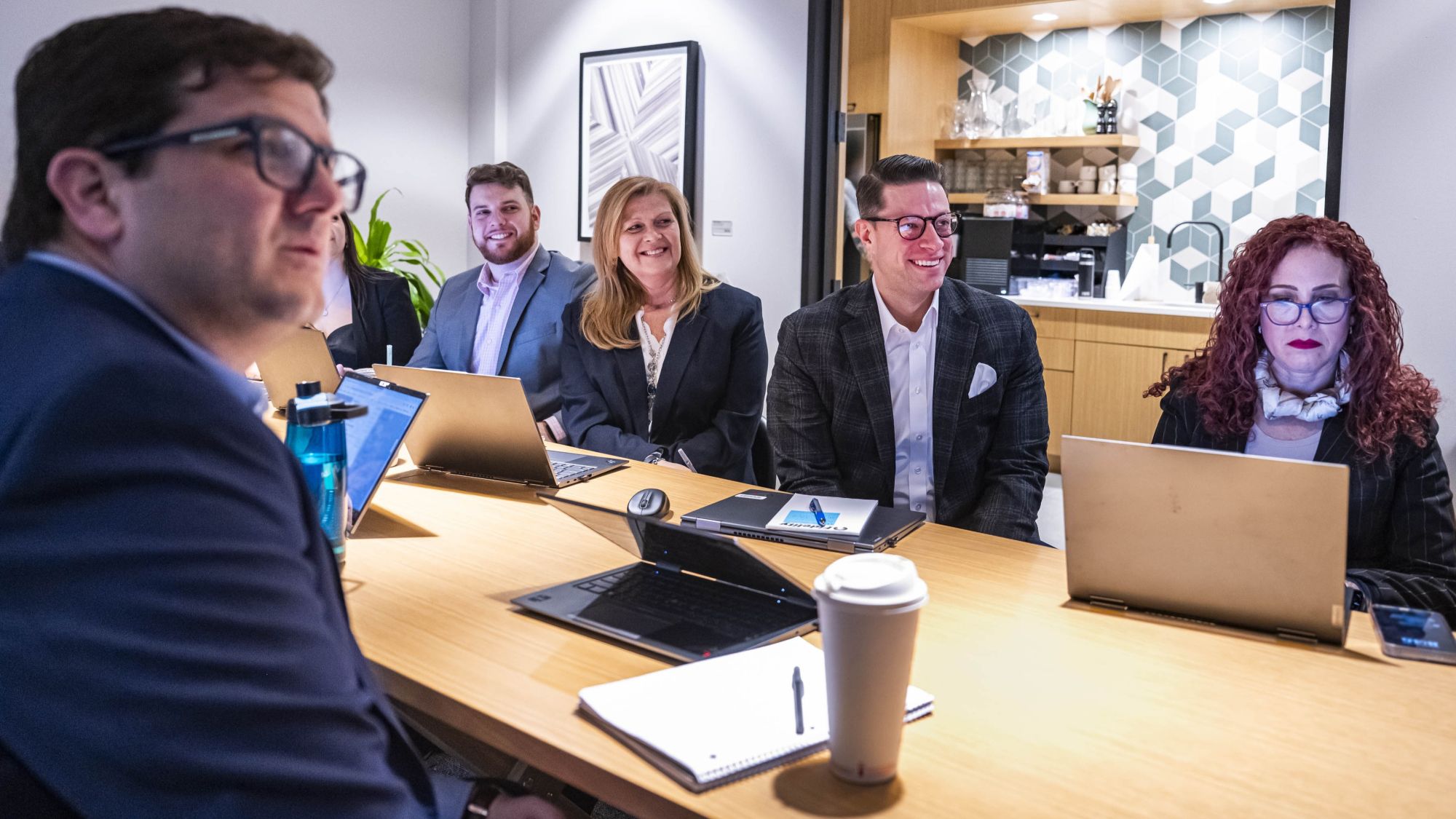 a group of people sitting at a table with laptops