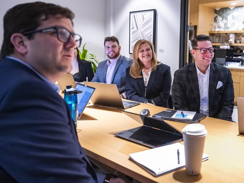 a group of people sitting at a table with laptops