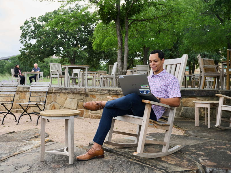 a person sitting in a rocking chair using a laptop