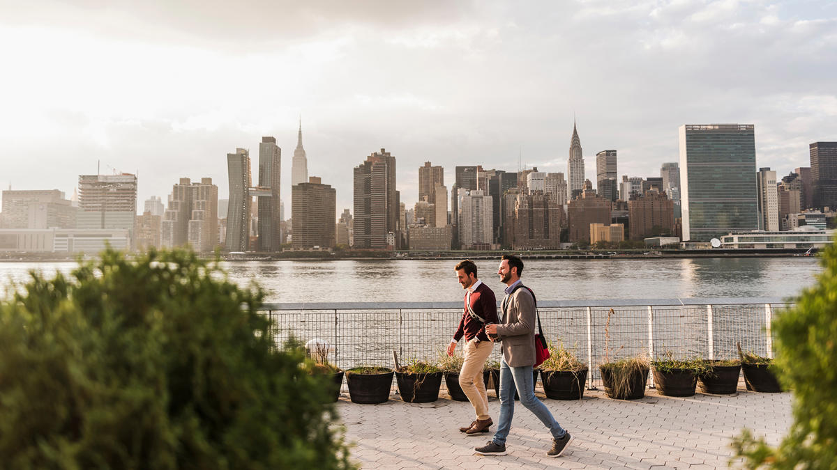 two men walking on a sidewalk near a body of water