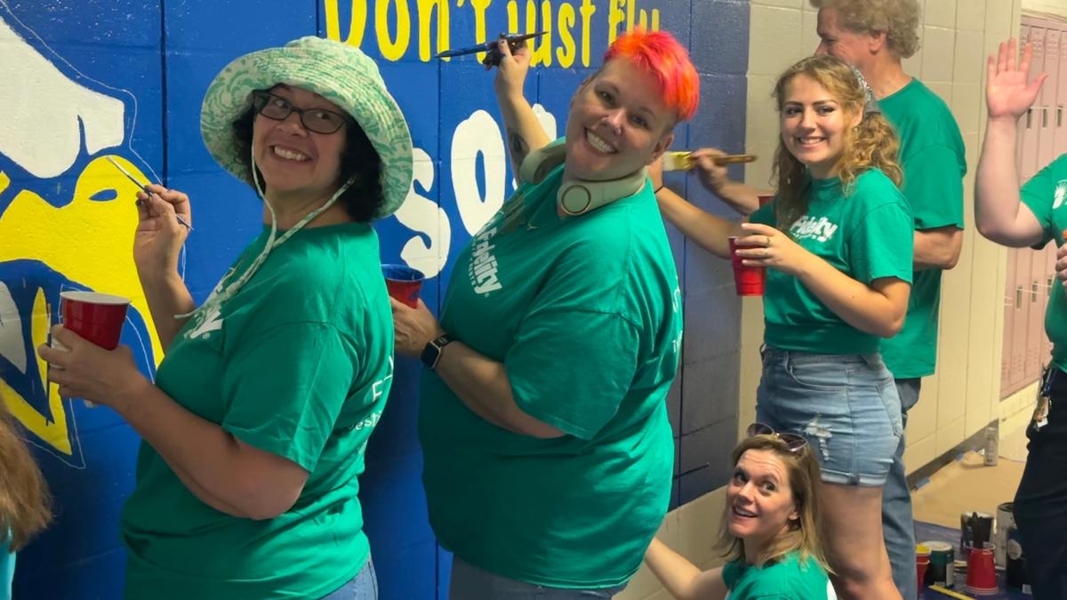 a group of women painting a wall