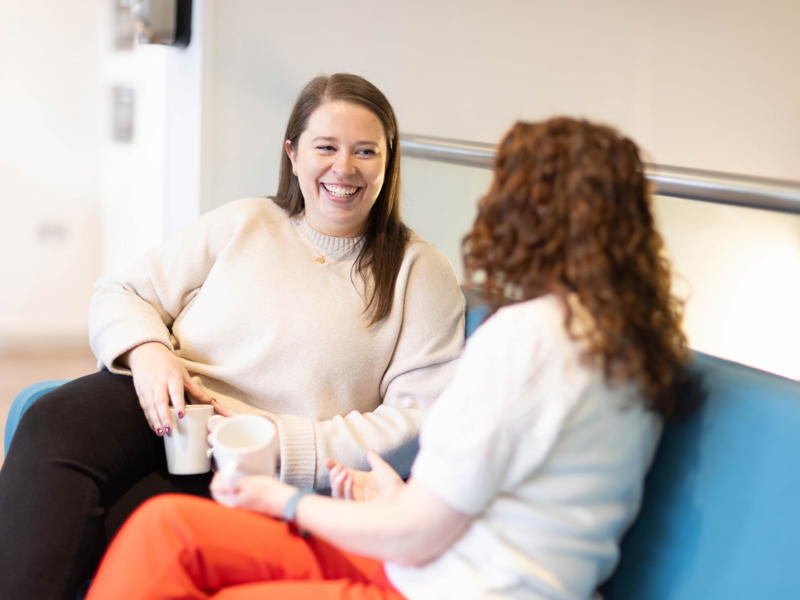 two women sitting on a blue couch