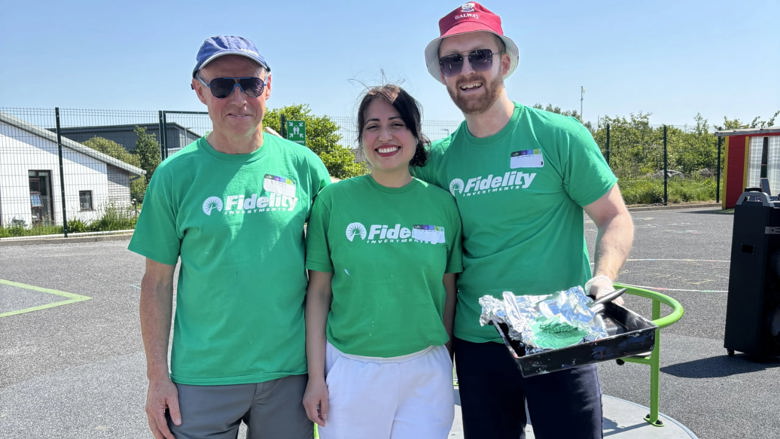 Three Fidelity associates standing together in green shirts while working at a charitable event