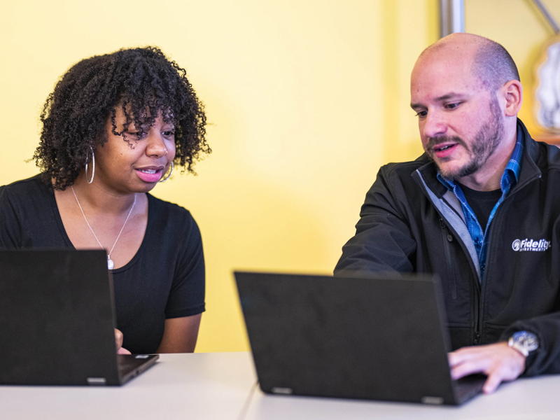 a person and person looking at laptops