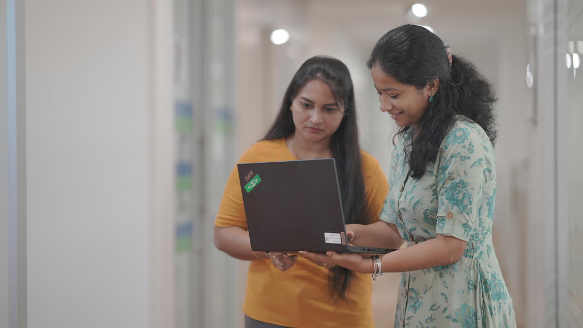 a couple of women looking at a laptop