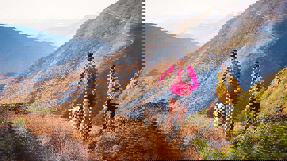 a couple of people running on a mountain