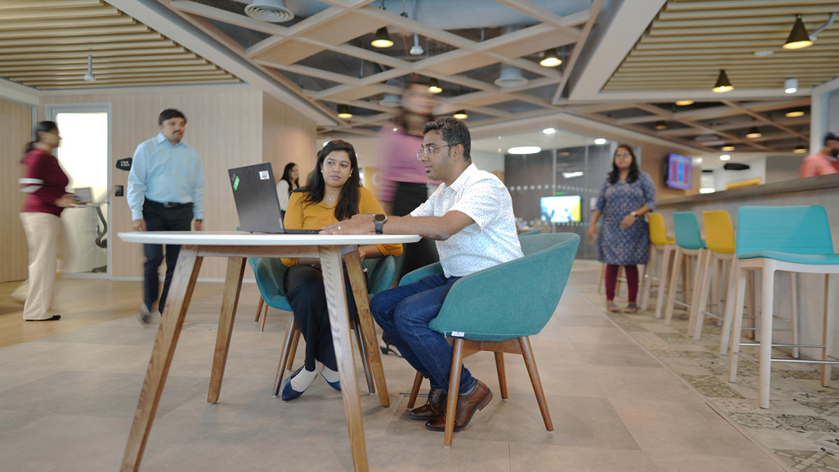 a person and person sitting at a table with a laptop