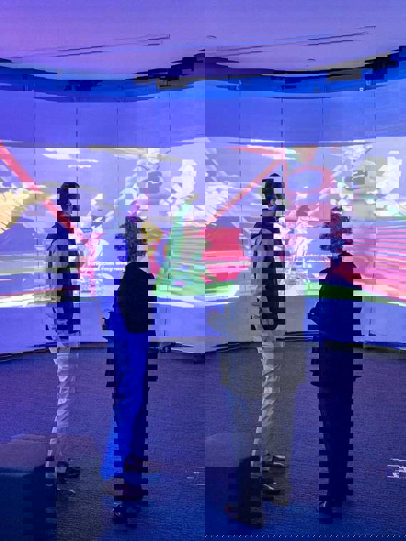 a person and person standing in a room with a large screen