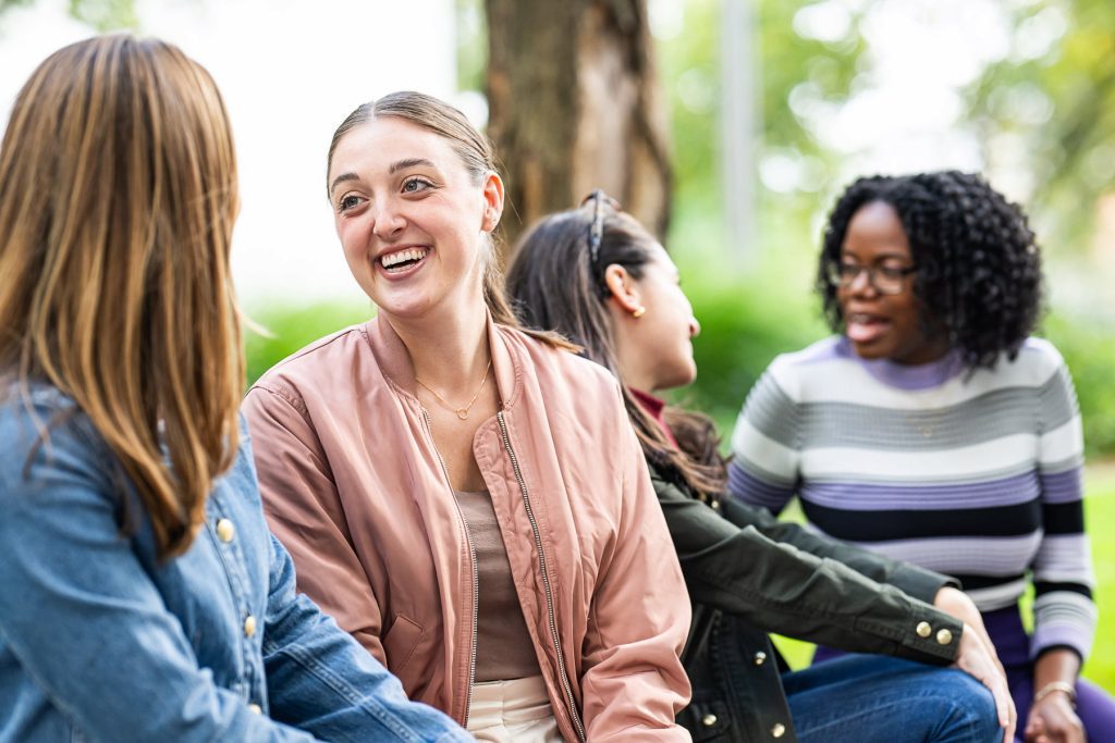 Two pairs of women each having conversations outdoors